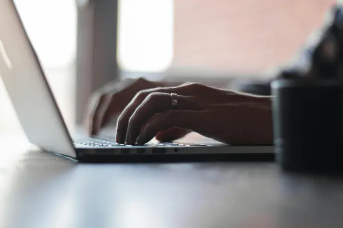 Close-up of hands typing on a laptop, symbolizing direct communication with Entropya’s team